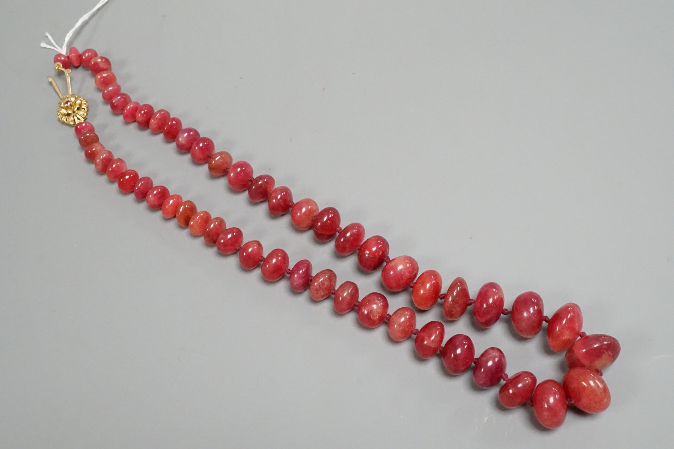 A modern single strand graduated polished ruby pebble necklace, with 585 yellow metal clasp, 54cm.